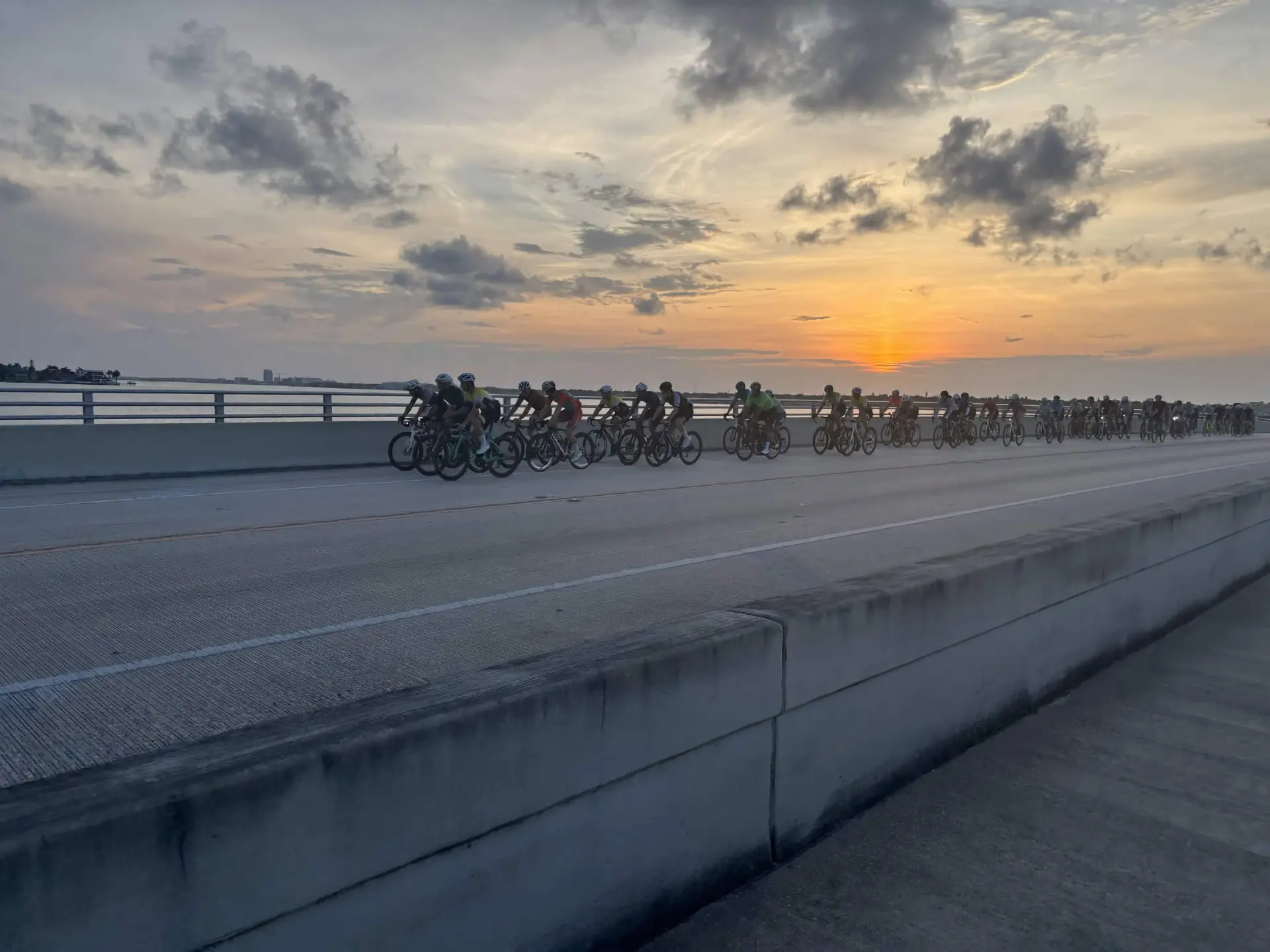 Cyclists riding a Florida causeway bridge at sunrise